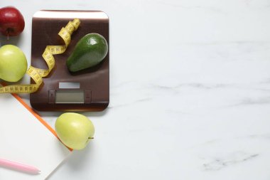 Elektronik mutfak ölçeği, mezura ve beyaz mermer masa üzerindeki ürünler düz konum. Metin için boşluk