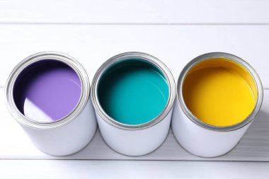 Beyaz ahşap masadaki parlak boya kutuları, yakın plan.