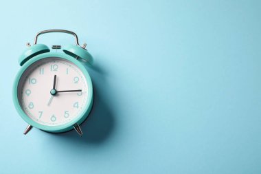 Açık mavi arka planda turkuaz alarm saati, üst manzara. Metin için boşluk