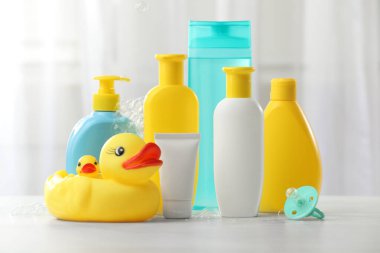 Bebek kozmetik ürünleri, emzik, plastik ördekler ve kapalı masa üzerinde uçan baloncuklar.