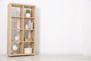 Shelving unit with different home decor near white wall indoors, space for text