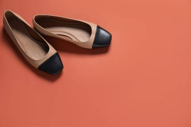 Kırmızı-kahverengi arka planda, düz bir çift şık ayakkabı. Metin için boşluk