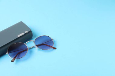Açık mavi arka planda şık güneş gözlüklü çanta. Metin için boşluk