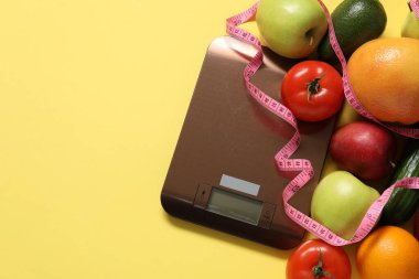 Elektronik mutfak ölçeği, ölçüm bandı ve sarı arka plandaki ürünler, düz alan. Metin için boşluk