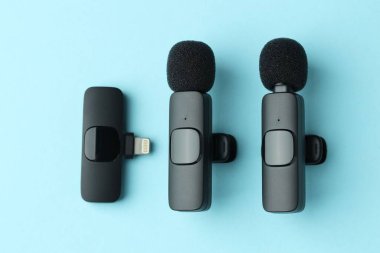 Lavalier mikrofonlar ve açık mavi zemin üzerinde kablosuz alıcı, düz yatıyordu