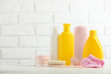 Bebek kozmetik ürünleri, çoraplar, emzik ve beyaz tuğla duvara sürtünmek. Metin için boşluk