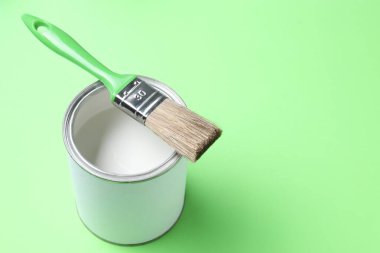 Açık yeşil arka planda beyaz boya ve fırça kutusu, yakın plan. Metin için boşluk