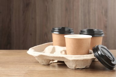 Tahta masadaki karton tutacakta kağıt kahve fincanları. Metin için boşluk