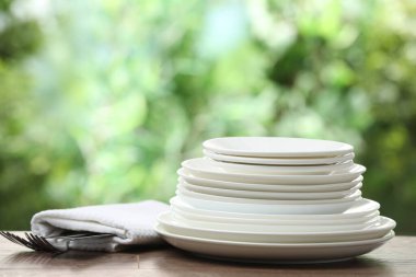 Clean dishware on wooden table against blurred background. Space for text