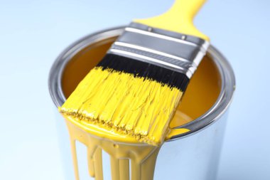 Açık arkaplanda sarı boya ve fırça kutusu, yakın plan.