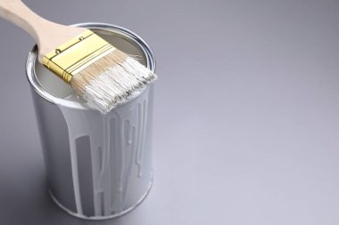 Gri arka planda beyaz boya ve fırça kutusu, yakın plan. Metin için boşluk