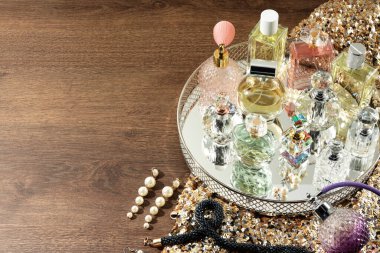 Ahşap masada farklı lüks parfümler ve aksesuarlar, metin için yer.