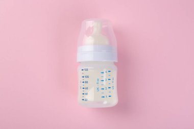 Pembe arka planda sütle beslenme şişesi, üst görünüm