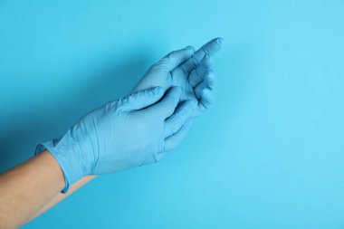 Doktor açık mavi arka plana tıbbi eldiven takıyor, yakın plan. Metin için boşluk