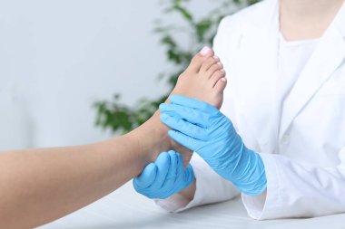 Hastanedeki hastanın ayağını muayene eden doktor, yakın plan.