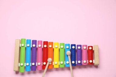 Pembe arka planda tokmakları olan renkli bir ksilofon. Metin için boşluk