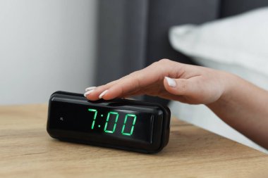 Kadın, başucundaki masanın dijital alarmını kapatıyor.