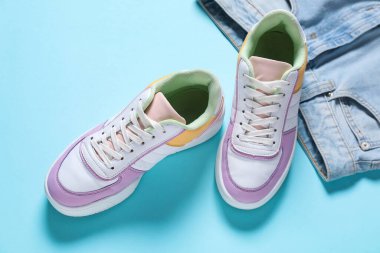 Açık mavi arka planda şık spor ayakkabılar ve kot pantolonlar.