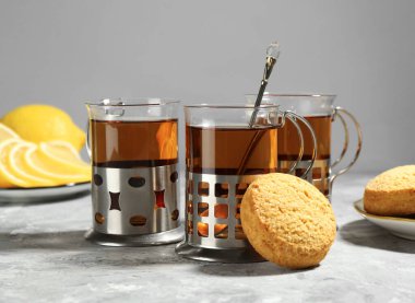 Gri desenli masada servis edilen metal tutacaklı çay bardakları.