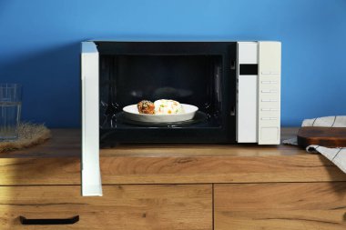 Mikrodalga fırını aç, pilav ve tavukla birlikte ahşap dolapta.