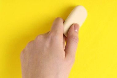 Sarı arkaplanda silgi kullanan kadın, yakın plan