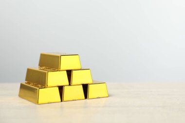 Altın külçeleri açık ahşap masada gri arka plana karşı, yakın plan. Metin için boşluk