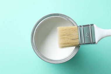Turkuaz arka planda beyaz boya ve fırça kutusu, üst görünüm
