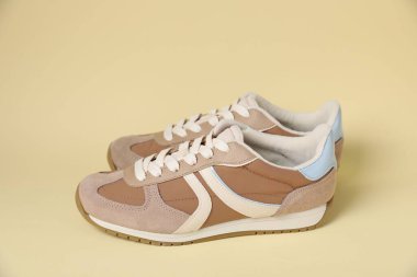 Pair of stylish sneakers on beige background. Casual shoes