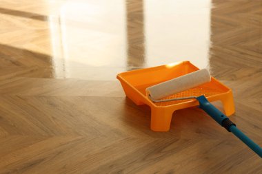 Process of polishing. Roller and tray with varnish on floor, space for text