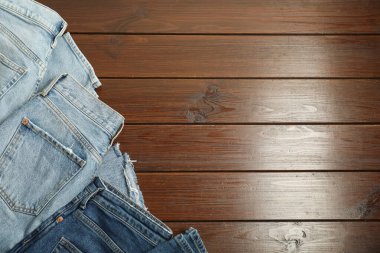Stylish jeans on wooden background, flat lay. Space for text