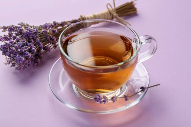 Cam bardakta Aromatik lavanta çayı ve pembe arka planda kuru çiçekler, yakın plan.