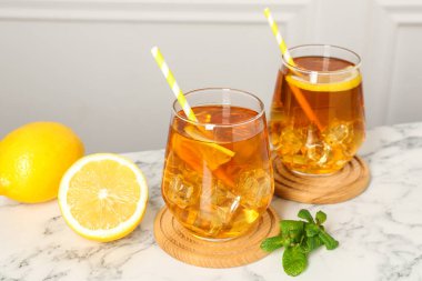 Buzlu çayı limon dilimleriyle, nane şekeriyle ve beyaz mermer masada pipet içerek tazeliyorum.