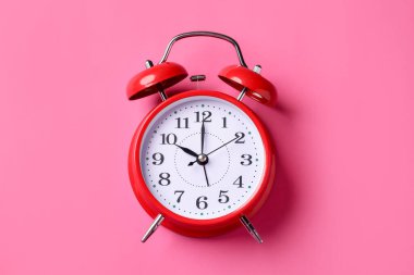 Pembe zemin üzerinde kırmızı alarm saati, üst görünüm
