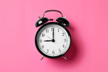 Pembe arka planda siyah alarm saati, üst görünüm