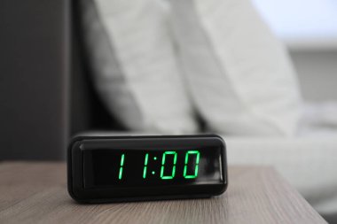 Dijital alarm saat 11 'de kapalı bir odada, komodinin yanında.