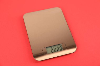 Kırmızı arka planda bir elektronik mutfak terazisi.