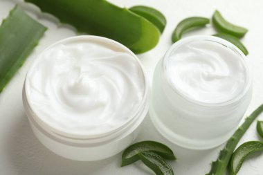 Aloe vera özütüyle nemlendirici krem ve beyaz desenli arka planda yapraklar, yakın plan
