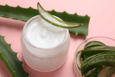 Kavanozda aloe vera özütüyle nemlendirici krem ve pembe arka planda yapraklar, yakın plan