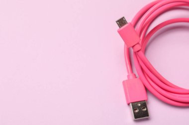 Pembe arka planda bir USB şarj kablosu, üst görüntü. Metin için boşluk
