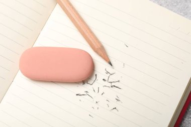 Eraser, pencil, notebook and scraps on table, top view