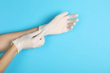 Doktor açık mavi arka plana tıbbi eldiven takıyor, yakın plan. Metin için boşluk