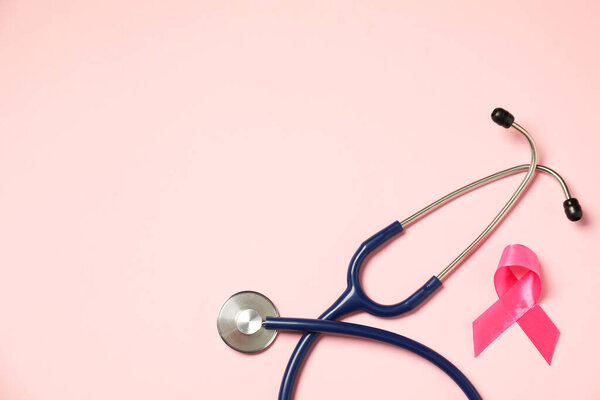 Breast cancer awareness. Pink ribbon and stethoscope on color background, flat lay. Space for text