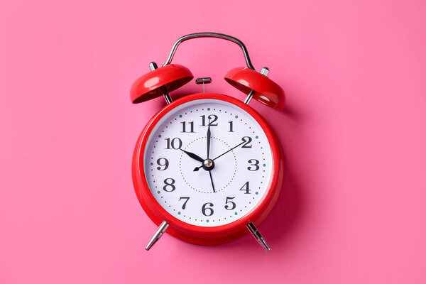Красный будильник на розовом фоне, вид сверху