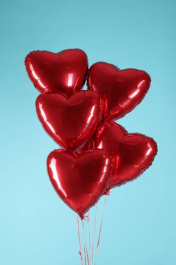 Açık mavi arka planda bir sürü kırmızı kalp şeklinde balon. Sevgililer Günün kutlu olsun.