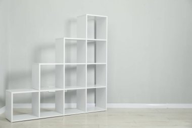 Empty shelving unit near light grey wall indoors, space for text