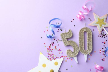 50. yaş günü. Numara şekilli mumlar, konfeti ve menekşe arka planda parti dekorasyonu, düz yatış. Metin için boşluk