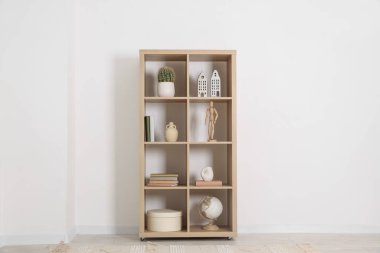 Beyaz duvarın yanında farklı dekorasyona sahip raf ünitesi.