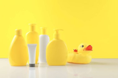 Bebek kozmetik ürünleri ve banyo aksesuarları sarı arka planda. Metin için boşluk