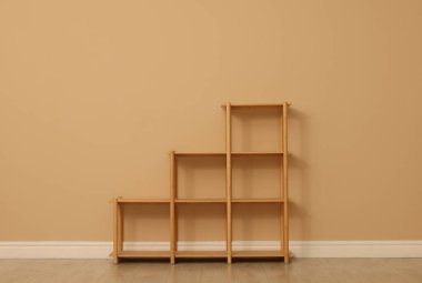 Bej duvarın yanındaki boş raf ünitesi.