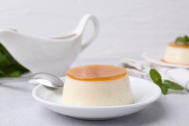 Beyaz masada servis edilen karamel soslu lezzetli puding, yakın plan.